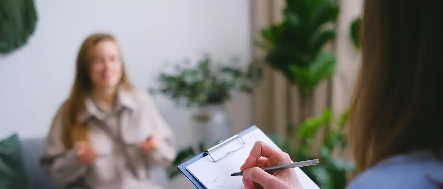 A counselling session — a counsellor takes notes while a client speaks